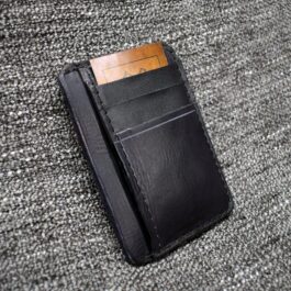 The "Michael" Wallet, a black leather wallet, laying on a carpet.