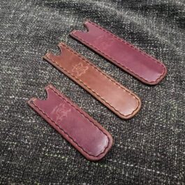 Three Leather Pen Pocket Slips sitting on top of a piece of cloth.
