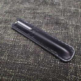 A Leather Pen Pocket Slip laying on a gray carpet.