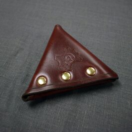 A triangle shaped Handmade Leather Coin Pouch sitting on top of a table.