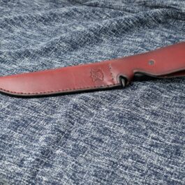A Vertical Leather Sheath for the SOG Tigershark laying on top of a blue cloth.