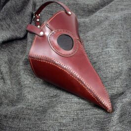red Handmade Leather Plague Doctor Mask laid on a cloth - renaissance clothing - renaissance clothing men - renaissance clothing women - renaissance clothing near me - renaissance art clothing - renaissance era clothing - renaissance costume ideas
