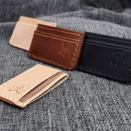 two leather wallets sitting on top of a bed.
