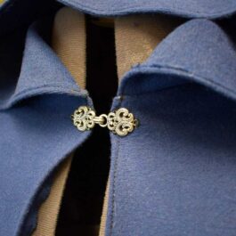 a close up of a Wool Hooded Cloak in blue with a bow tie.
