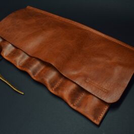 A handmade leather knife/tool roll with a gold zipper.