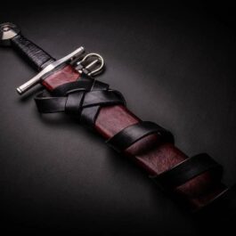 A Custom Wood Core Scabbard with a leather strap and a metal blade.
