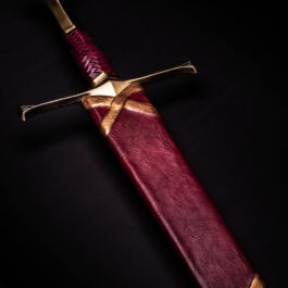 A red and gold sword in a Custom Wood Core Scabbard on a black background.