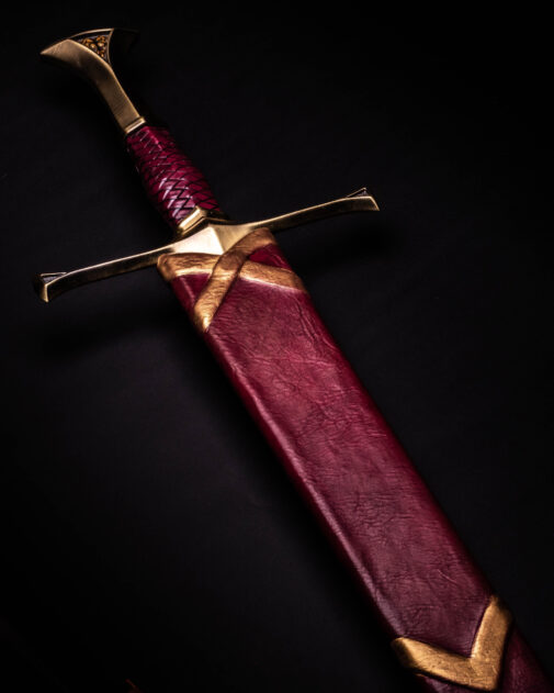 A red and gold sword in a Custom Wood Core Scabbard on a black background.