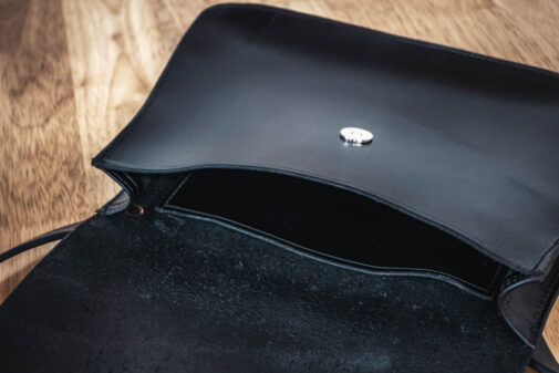 A black "Serenity" purse sitting on top of a wooden table.
