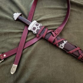 a leather sword laying on top of a bed.