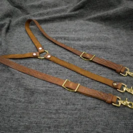 A pair of Bison Leather Suspenders on a gray cloth.