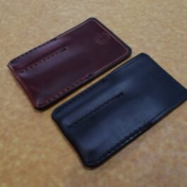Two Handmade Leather 2 Slot Pocket Organizers sitting on top of a table.