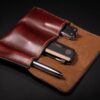 A Handmade Leather 3 Slot Pocket Organizer with a pen and a lighter in it.