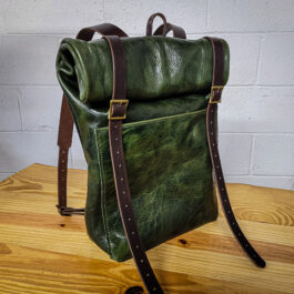 A bison leather roll top rucksack sitting on top of a wooden table.
