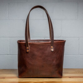 A Horween Leather Tote Bag sitting on top of a wooden table.