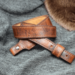 Folded light brown Bison Leather Cobra Sling without attachments and a fur cloth in the background - Grommet's Leathercraft - renaissance clothing - renaissance art clothing - renaissance era clothing - leathercraft supplies - leathercraft accessories - leathercraft store near me - quality leather craft