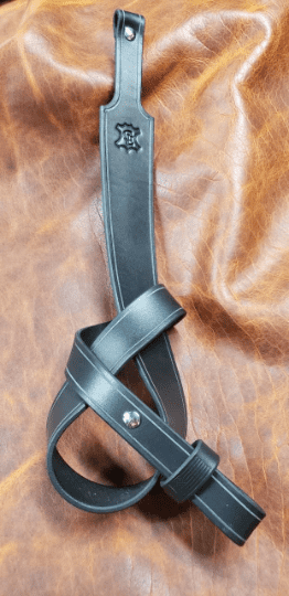 A black Handmade Leather Cobra Rifle Sling laid on a leather cloth - Grommet's Leathercraft - renaissance clothing - renaissance art clothing - renaissance era clothing - leathercraft supplies - leathercraft accessories - leathercraft store near me - quality leather craft