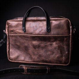 A Bison Leather Briefcase Satchel sitting on top of a black table.
