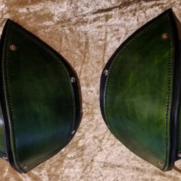 a pair of green Leather Shoulder Armor Style 2s sitting on top of a bed.
