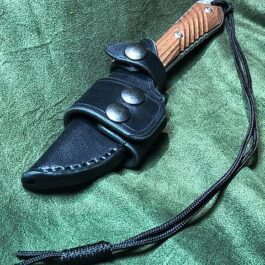 Leather Scout Sheath for the Chris Reeve Nyala that is laying on a green cloth.
