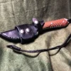 A Leather Scout Sheath for the Chris Reeve Nyala that is laying on a cloth.