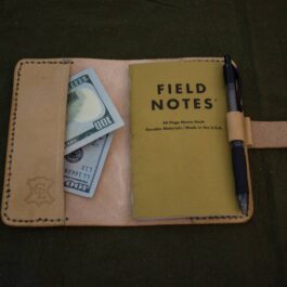A Leather Field Notes Cover with a notepad and a pen on top of it.