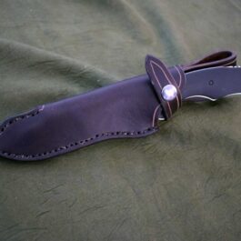 A Benchmade Fixed Contego knife with a Leather Sheath for the Benchmade Fixed Contego on a green cloth.