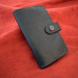A Leather Field Notes Cover sitting on top of a red blanket.
