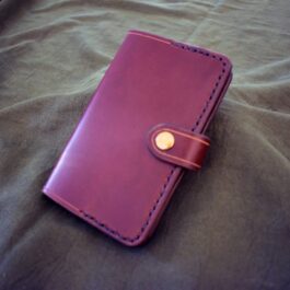 A purple Leather Field Notes Cover sitting on top of a bed.