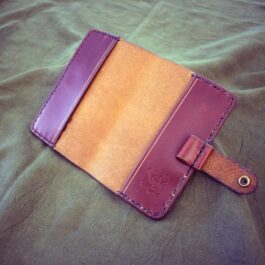 a leather field notes cover laying on a bed.