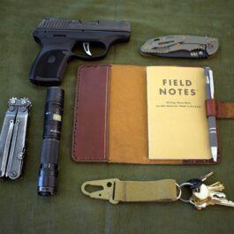 A Leather Field Notes Cover, a notebook, keys, and a lighter on a table.