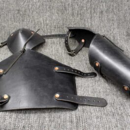 A pair of Leather Vambraces with Attached Elbow Armor sitting on top of a couch.