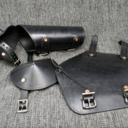 A couple of Leather Vambraces with Attached Elbow Armor sitting on top of a couch.