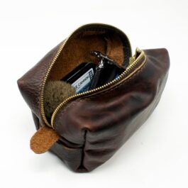 A brown Leather Dopp Kit/Toiletry Bag with a cell phone inside.