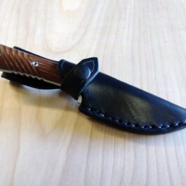 A Chris Reeve Nyala knife with a Vertical Leather Sheath on a wooden table.