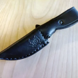 A Vertical Leather Sheath for the Chris Reeve Nyala with a black handle on a wooden table.