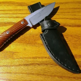 a Chris Reeve Nyala knife on a wooden table with a Vertical Leather Sheath for the Chris Reeve Nyala.