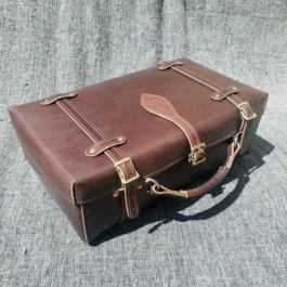 A Handmade Leather Suitcase sitting on top of a couch.