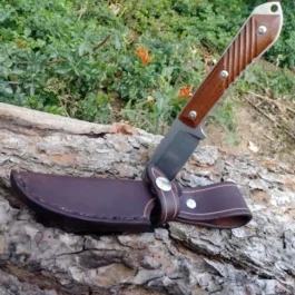 A Vertical Leather Sheath for the Chris Reeve Nyala that is sitting on top of a rock.