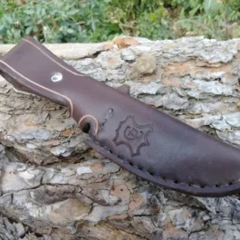 A Vertical Leather Sheath for the Chris Reeve Nyala sitting on top of a tree.