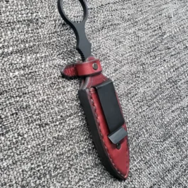 A Handmade leather Sheath for the Benchmade SOCP Dagger laying on top of a carpet.