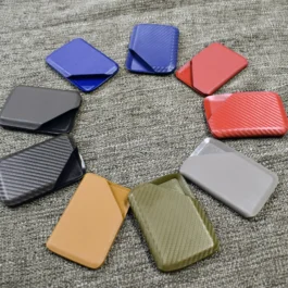 A group of different colored Kydex wallets sitting on top of a bed.