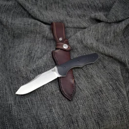 A Leather Sheath for the Benchmade Fixed Contego that is laying on top of a cloth.
