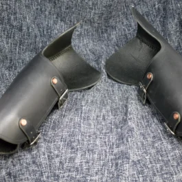 A pair of handmade black leather Bazuband Style 2 shoes on a blue cloth.