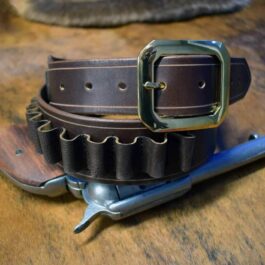A Cartridge Gun Belt with a metal buckle on a wooden table.