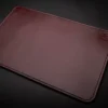 A brown leather Handmade Leather Mouse Pad on a black surface.