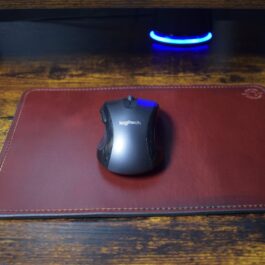 A handmade leather mouse pad sitting underneath a computer mouse.