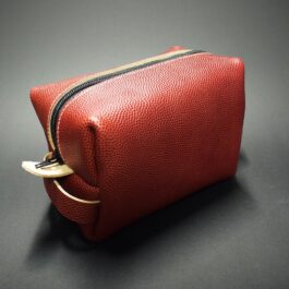 red Football Leather Dopp Kit/Toiletry Bag laid on a black table - renaissance clothing - renaissance clothing men - renaissance clothing women - renaissance clothing near me - renaissance art clothing - renaissance era clothing - renaissance costume ideas