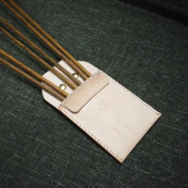 A close up of a Leather Pocket Quiver containing chopsticks.