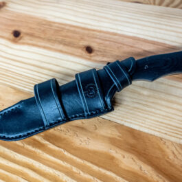 A Benchmade Fixed Contego knife with a black Leather Sheath for the Benchmade Fixed Contego on a wooden table.